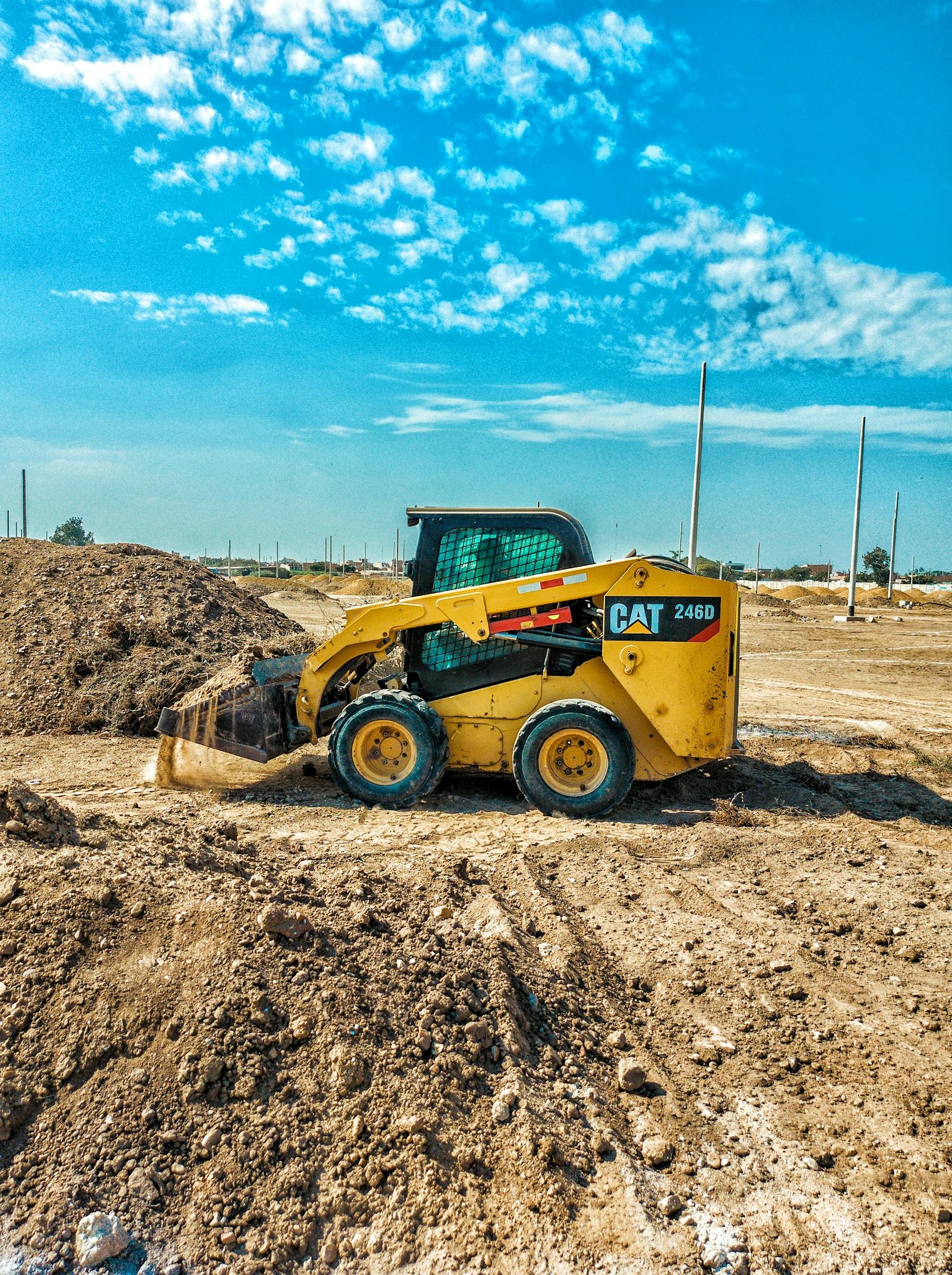Skid steer loader at a daytime construction site with blue sky backdrop.